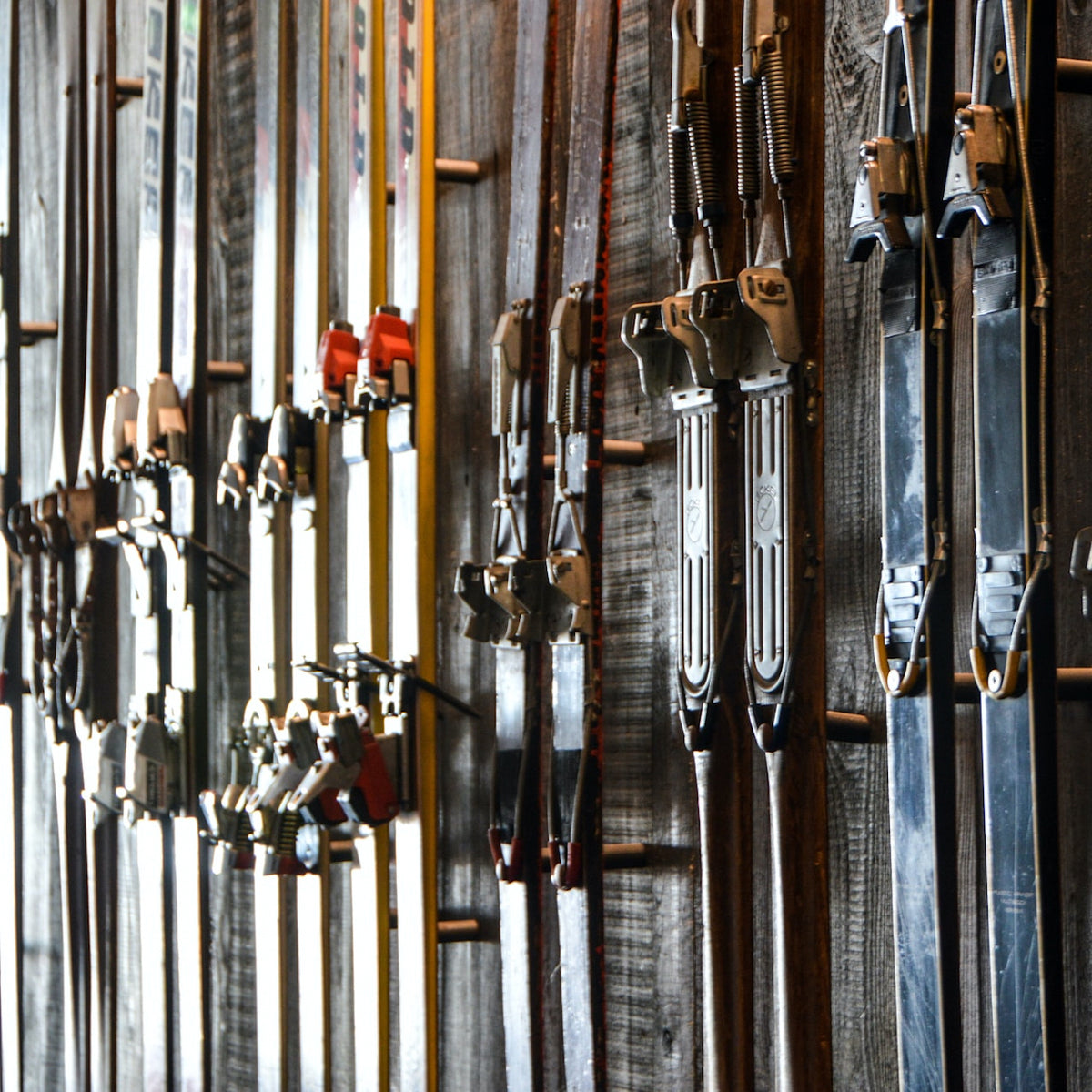A wall of skis lined up with the bindings arranged in the center of the photo