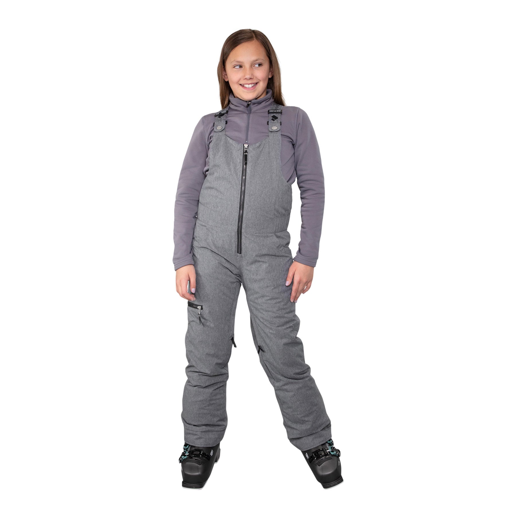 Hero image featuring a model wearing the Obermeyer girls Anya Bib Pant in light grey with black ski boots and a light grey long sleeve.