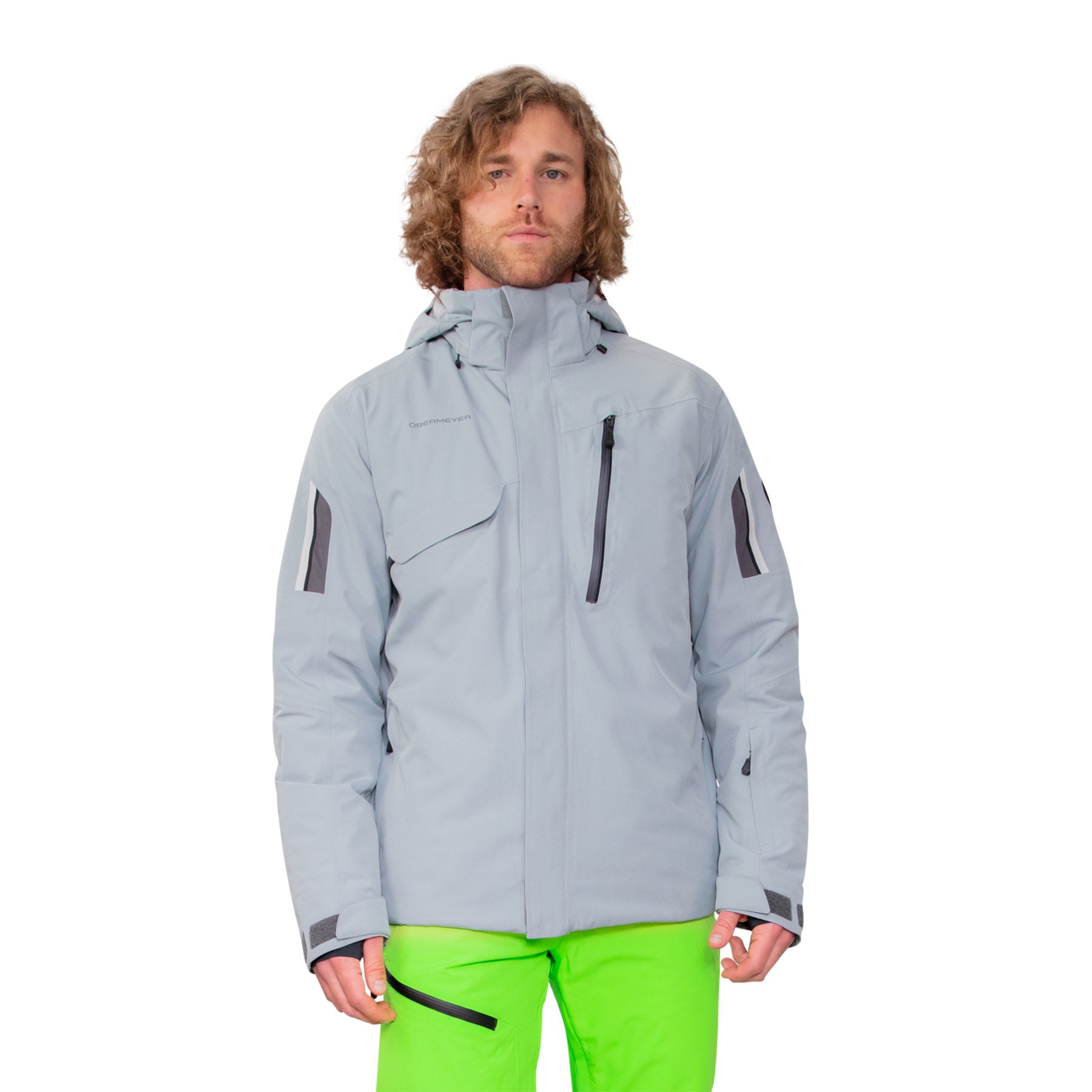 Hero image featuring a model wearing the Obermeyer Primo Jacket in shale grey with bright green ski pants.