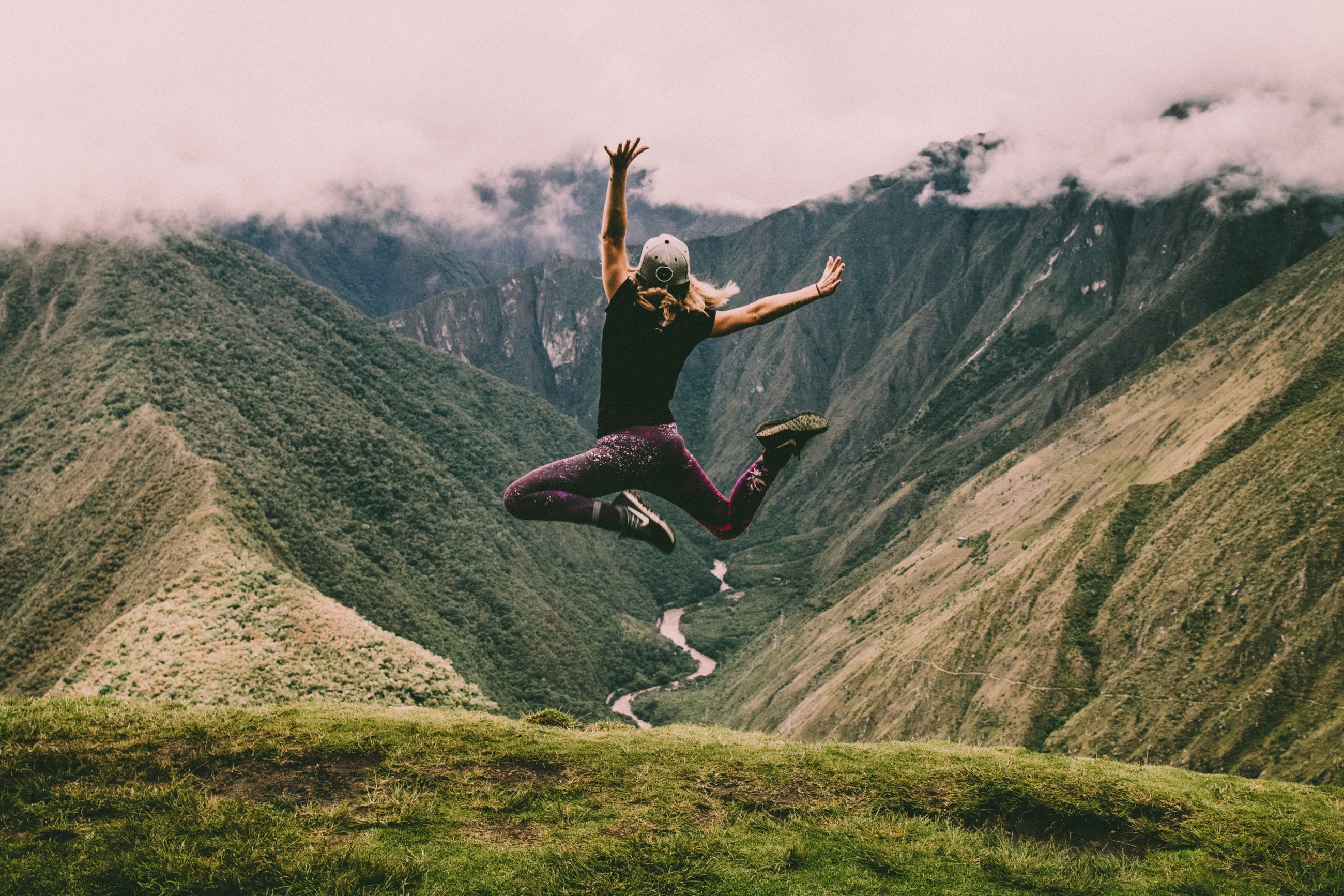 Hero image featuring a women jumping for joy while overlooking a beautiful mountain vista