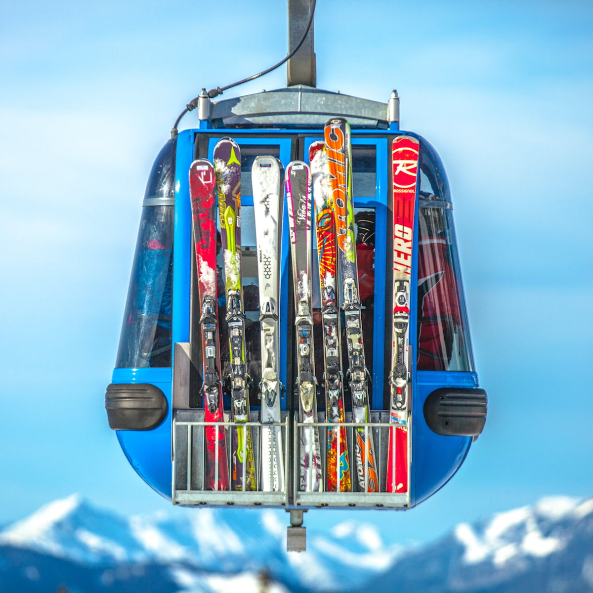 A gondola carrying 8 pairs of different colored skis up the mountain.
