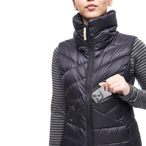Image features a female model pulling a cell phone out of the front pocket of the Indyeva Kapa sleeveless down vest.