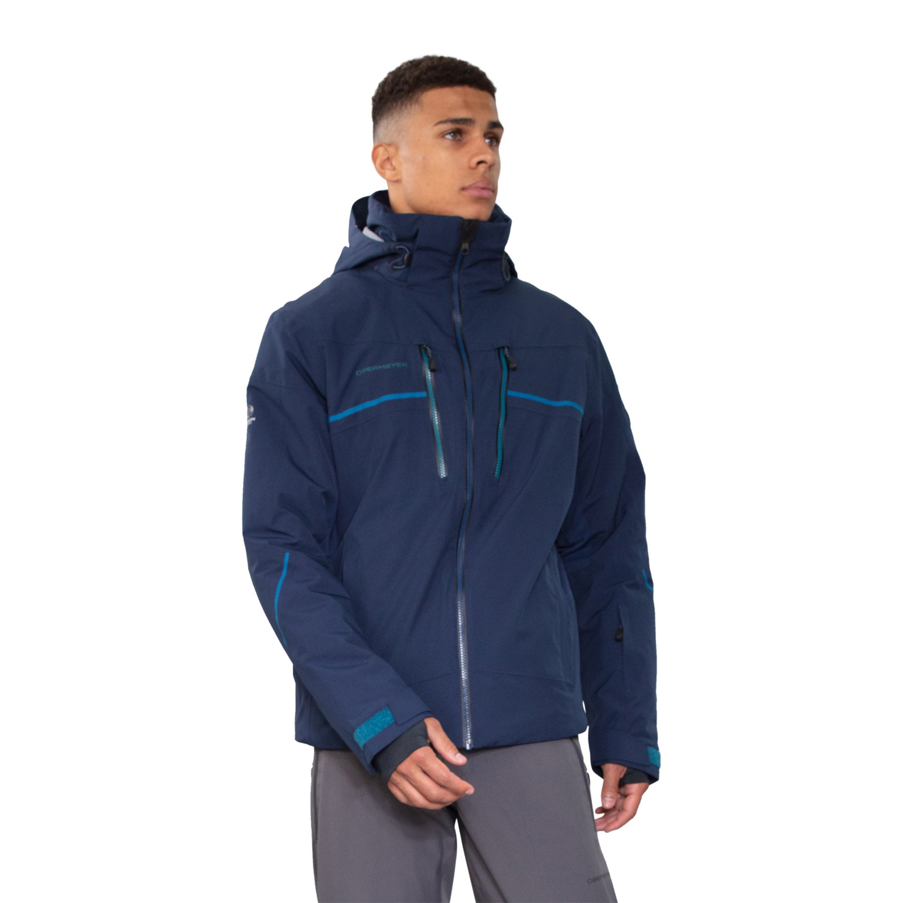 Hero image featuring a male model wearing the Obermeyer Charger jacket in admiral blue with light grey ski pants.