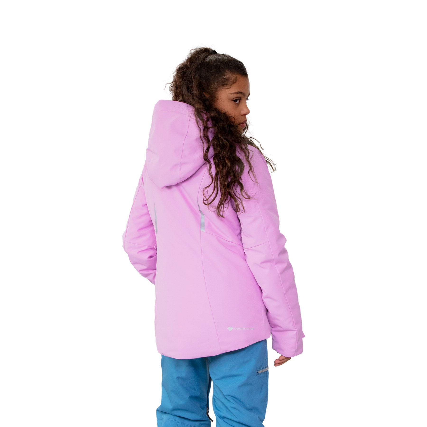 Hero image featuring the back of a female model wearing the Obermeyer Leia Jacket in fairytale light purple with blue ski pants.