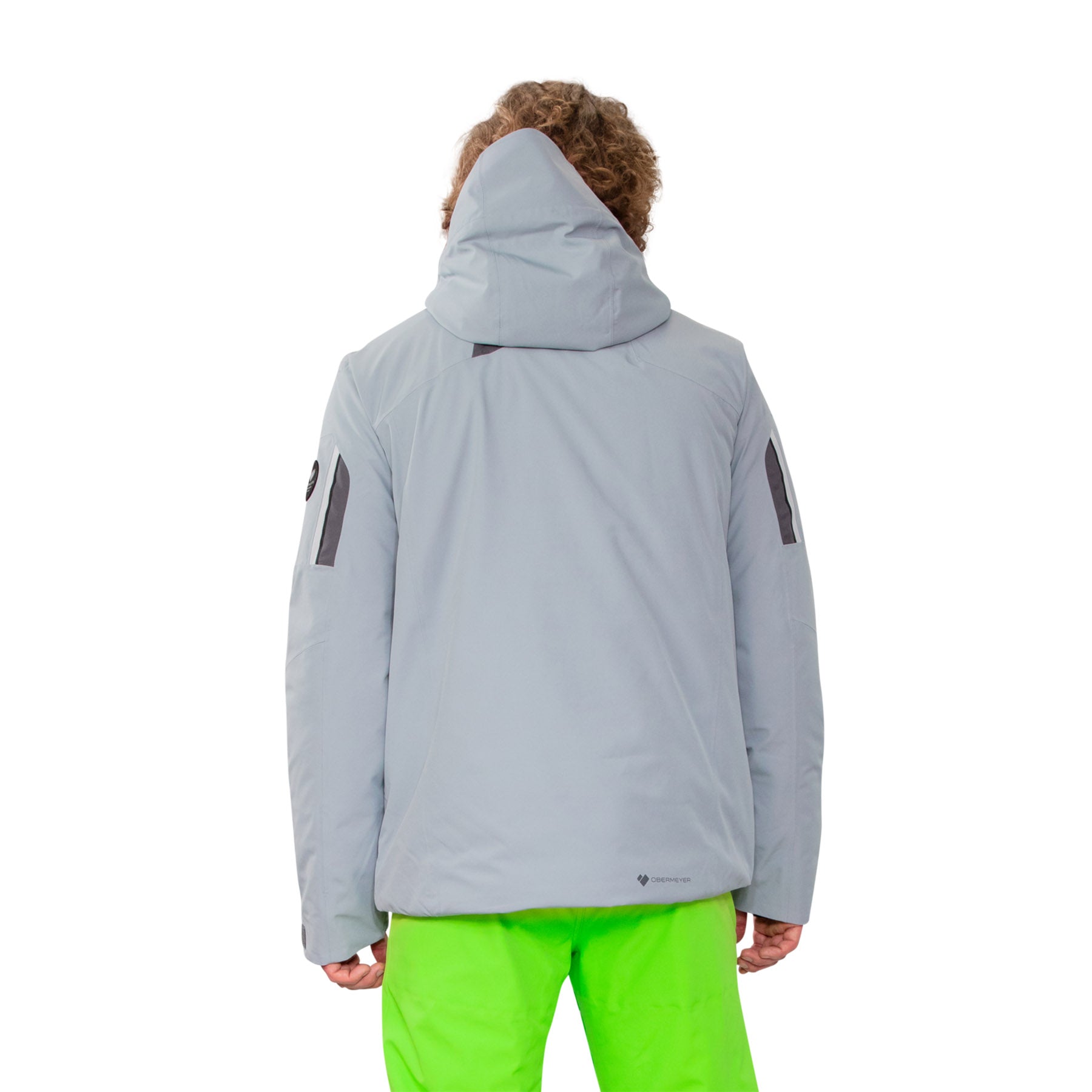 Image features the back of a model wearing the Obermeyer Primo Jacket in shale grey with bright green ski pants.