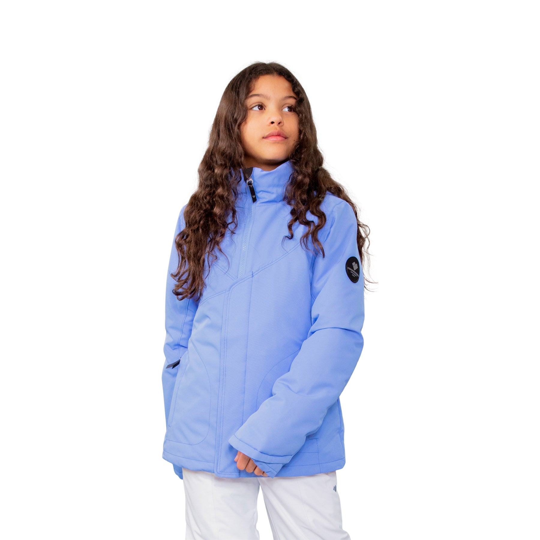 Image features a female model wearing the Obermeyer girls Rylee Jacket in Vinca light purple with white ski pants.