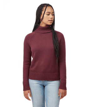 Hero image featuring a female model wearing blue jeans and the Ten Tree Highline wool sweater in fig red.