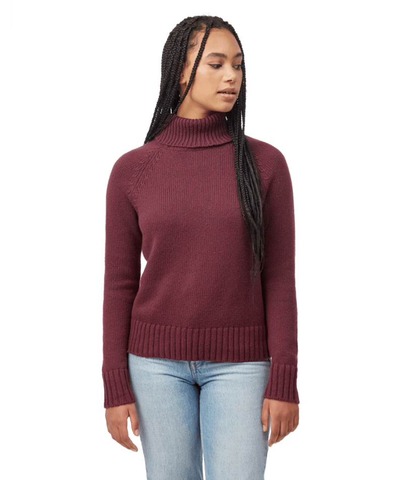 Hero image featuring a female model wearing blue jeans and the Ten Tree Highline wool sweater in fig red.